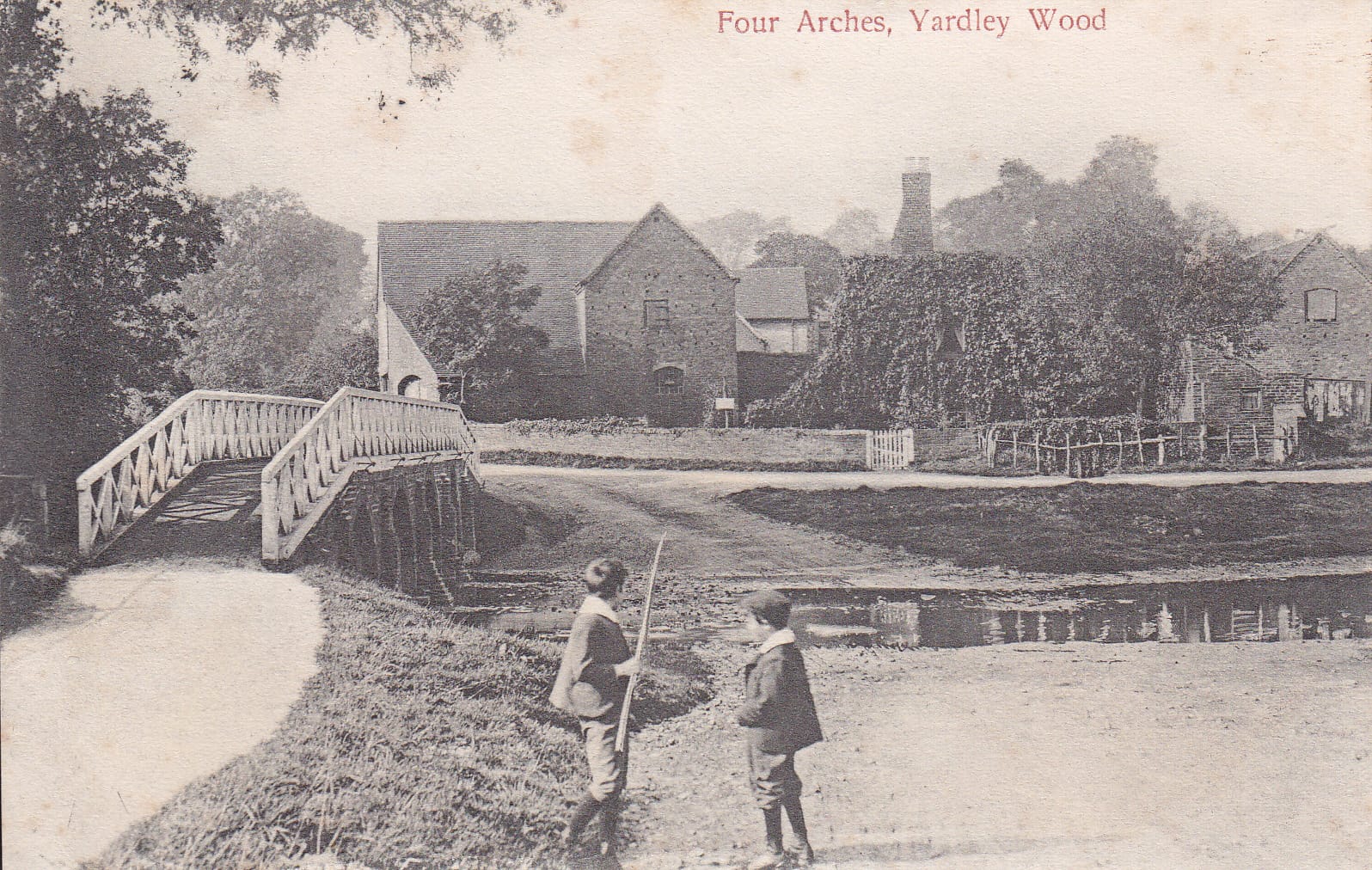The Four Arches bridge over the River Cole in 1905, with boys beside the ford